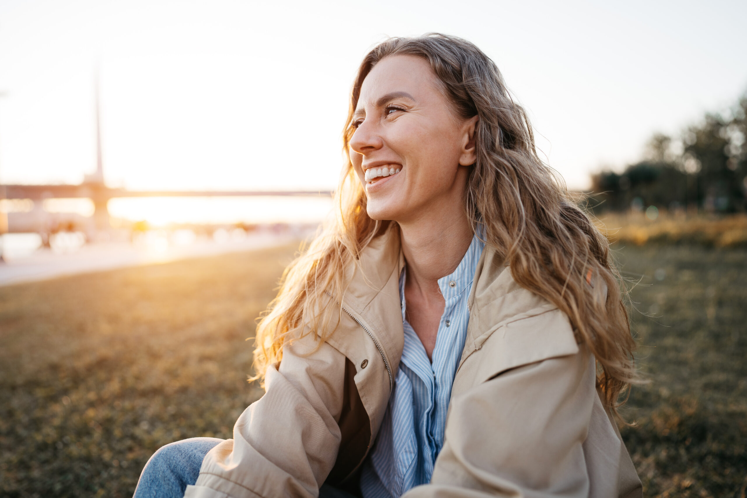 Smiling woman sitting outdoors at sunset