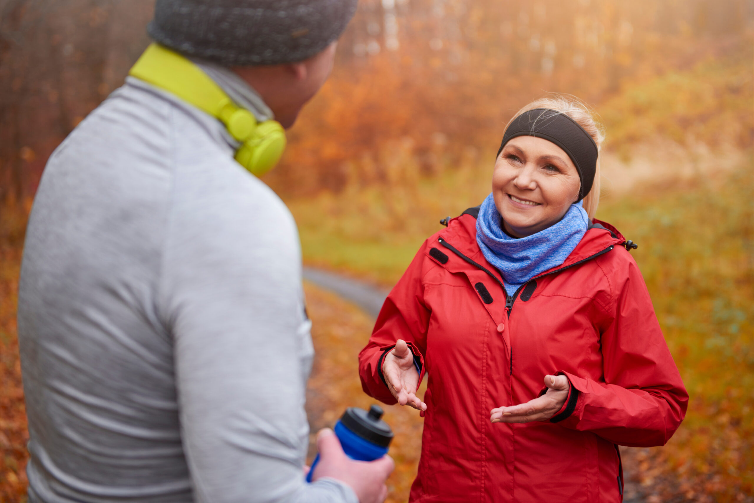 Woman in a red jacket chatting with a man on an autumn walk